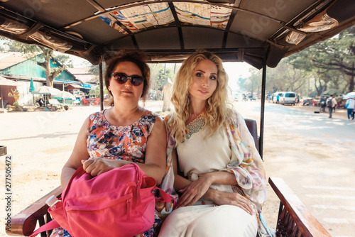 Women in tuk-tuk asian taxi: mother and daughter travelling to Angkor Wat, Siem Reap, Cambodia photo