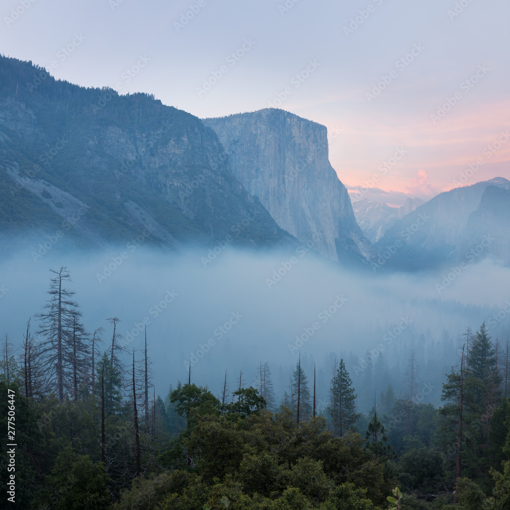 Classic Tunnel View of scenic Yosemite Valley with famous El Capitan and Half Dome rock climbing summits in beautiful misty atmosphere at morning in summer, Yosemite National Park, California, USA