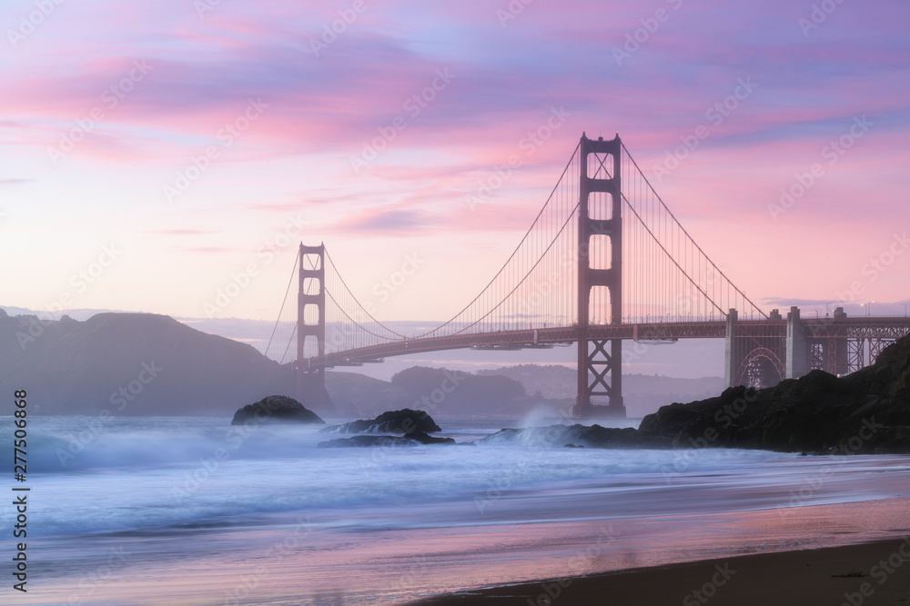 Obraz premium Classic panoramic view of famous Golden Gate Bridge seen from scenic Baker Beach in beautiful golden evening light on sunset with blue sky and clouds in summer, San Francisco, California, USA