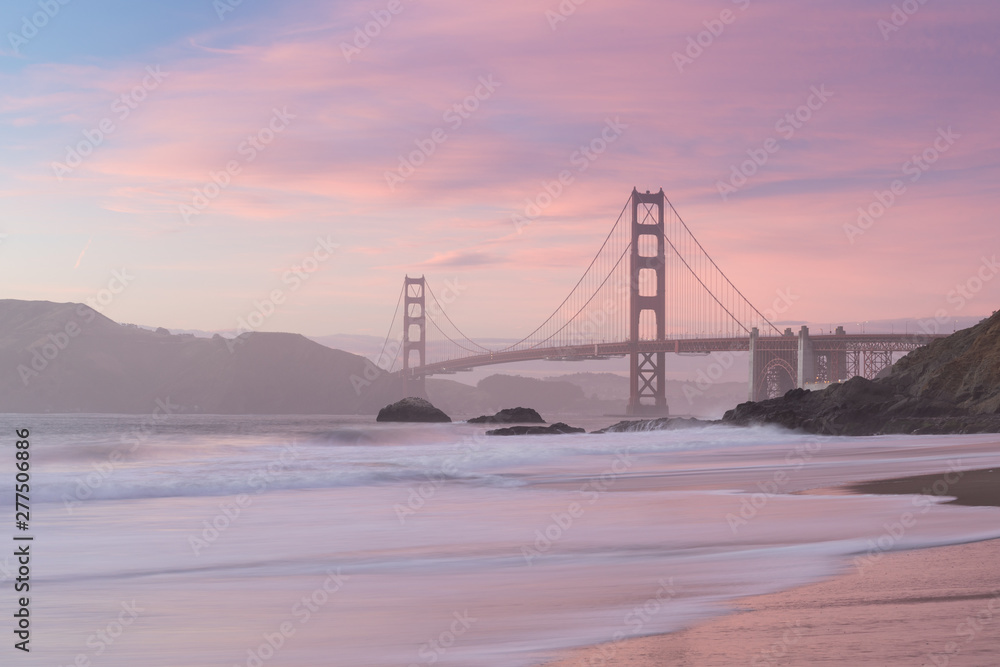Obraz premium Classic panoramic view of famous Golden Gate Bridge seen from scenic Baker Beach in beautiful golden evening light on sunset with blue sky and clouds in summer, San Francisco, California, USA