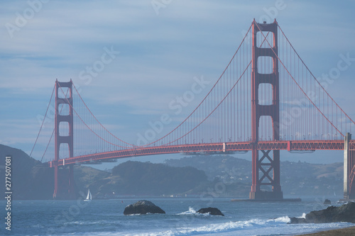 Classic panoramic view of famous Golden Gate Bridge seen from scenic Baker Beach in beautiful golden evening light on sunset with blue sky and clouds in summer, San Francisco, California, USA
