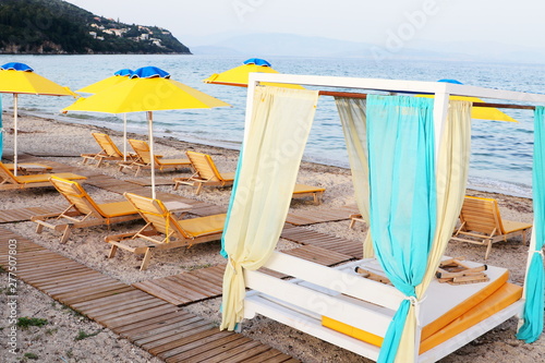 Yellow beach umbrella with foldable cots and wooden boardwalk
