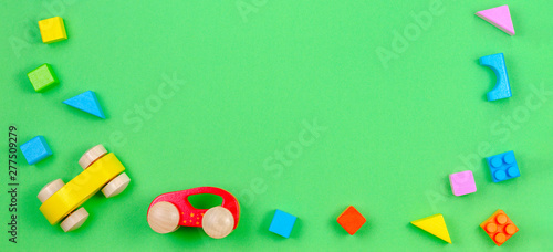 Baby kid toys banner background. Colorful wooden cubes and two cars on green background