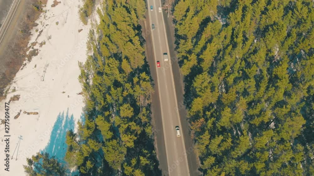 brown lively roadway runs along wide highway crossing green thick spring pine forest under bright sunlight aerial view brown lively roadway runs along wide highway crossing green thick spring pine forest under bright sunlight aerial view