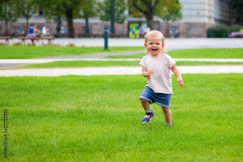 laughing baby girl running on the green grass