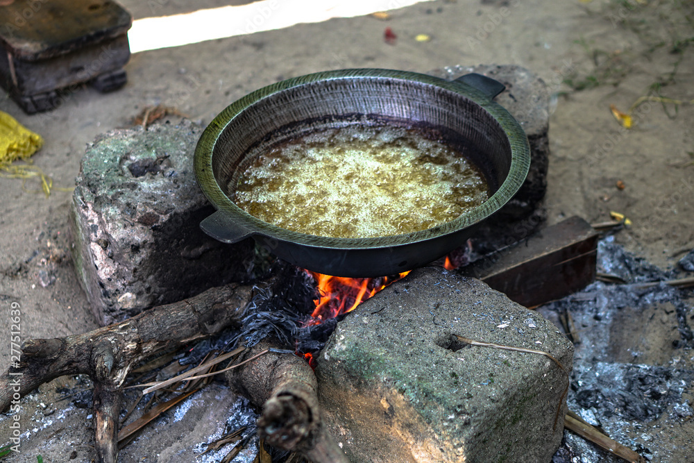 Coconut oil is covered in a large pot on the fire. Exotic countries of Asia and home life. Stock photo Coconut oil is covered in a large pot on the fire. Exotic countries of Asia and home life. Stock photo