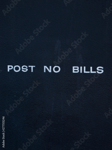 A sign on a wall prohibits posting bills to it. Very clean only with graphics.