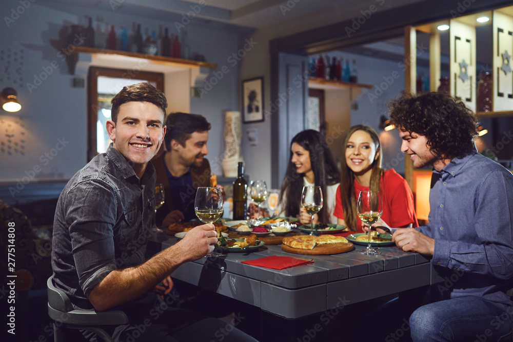 Man with a glass against the background of friends in a restaurant. Man with a glass against the background of friends in a restaurant.