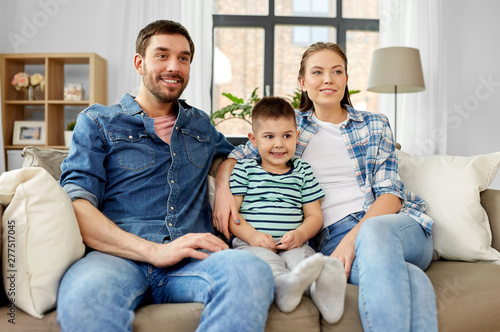 family, childhood and fatherhood concept - portrait of happy father, mother and little son sitting on sofa at home