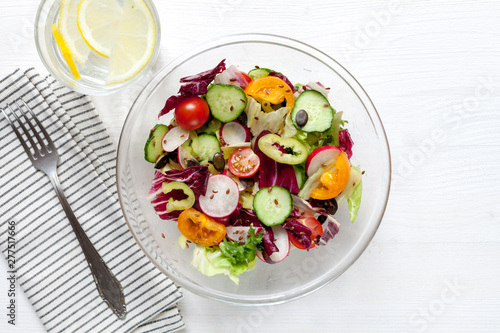 Salad with tomatoes, cucumbers, peppers, herbs and lemonade on white table. Healthy food concept