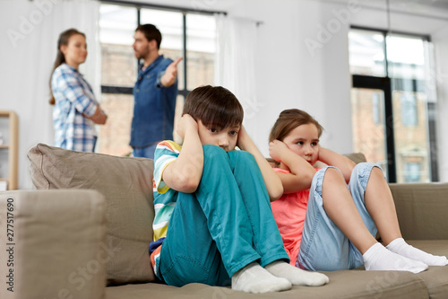 family problem, conflict and people concept - sad children closing ears while their parents quarreling at home