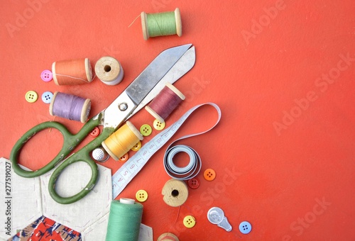 Accessories and accessories for sewing on a red background. Scissors, thread, accessories with space for your text.