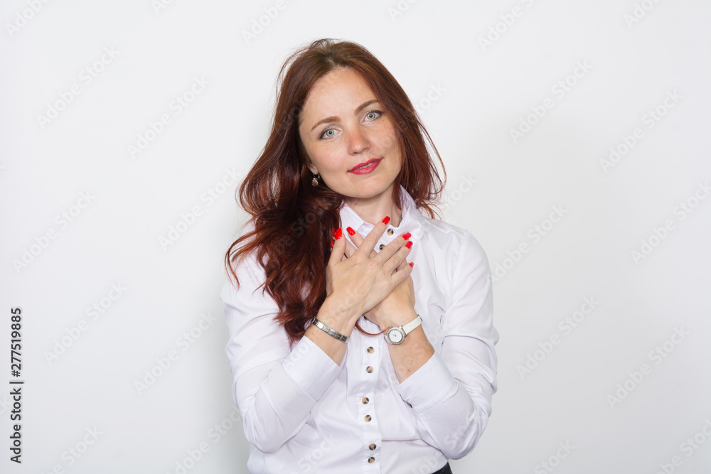 Red-haired woman in a bright blouse with hands clasped together on a white Red-haired woman in a bright blouse with hands clasped together on a white