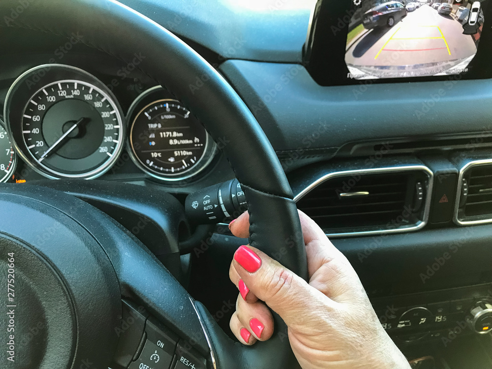 Female hand on the steering wheel inside the car.