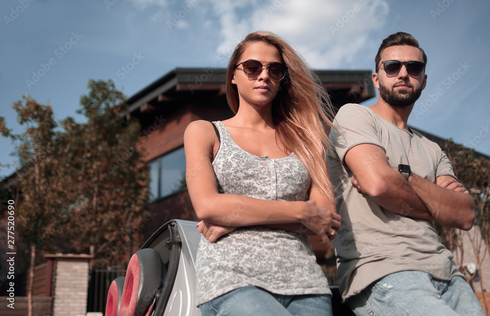 Naklejka premium bottom view.beautiful couple standing near a convertible car