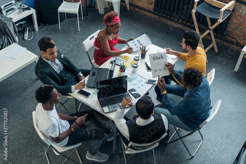 A team of young people confers and discusses the growth of investment at work. Business