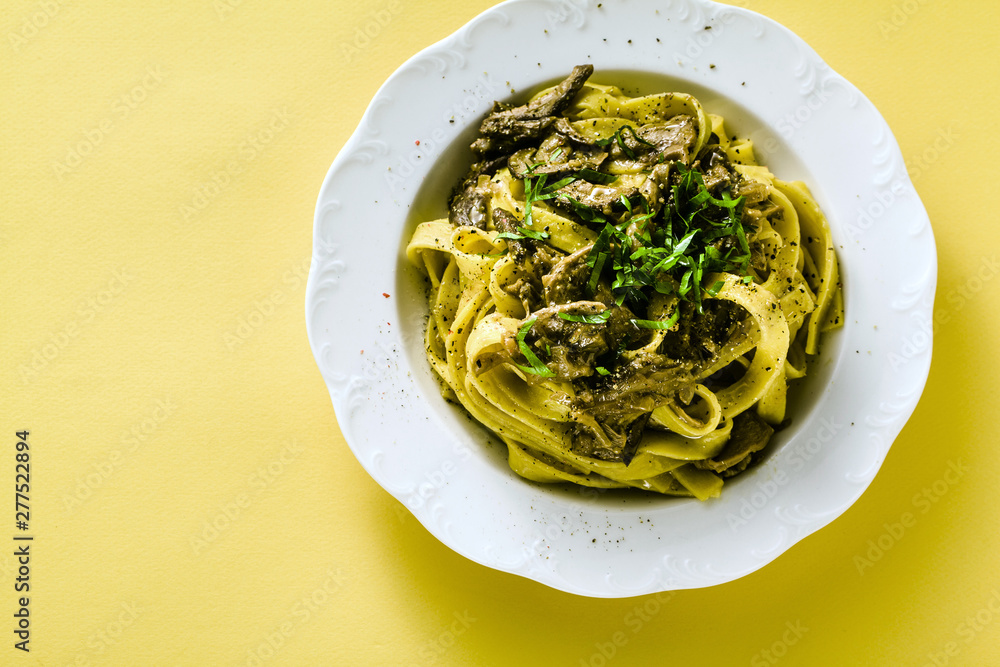 fresh italian pasta tagliatelle with porcini mushrooms in a plate on a white background