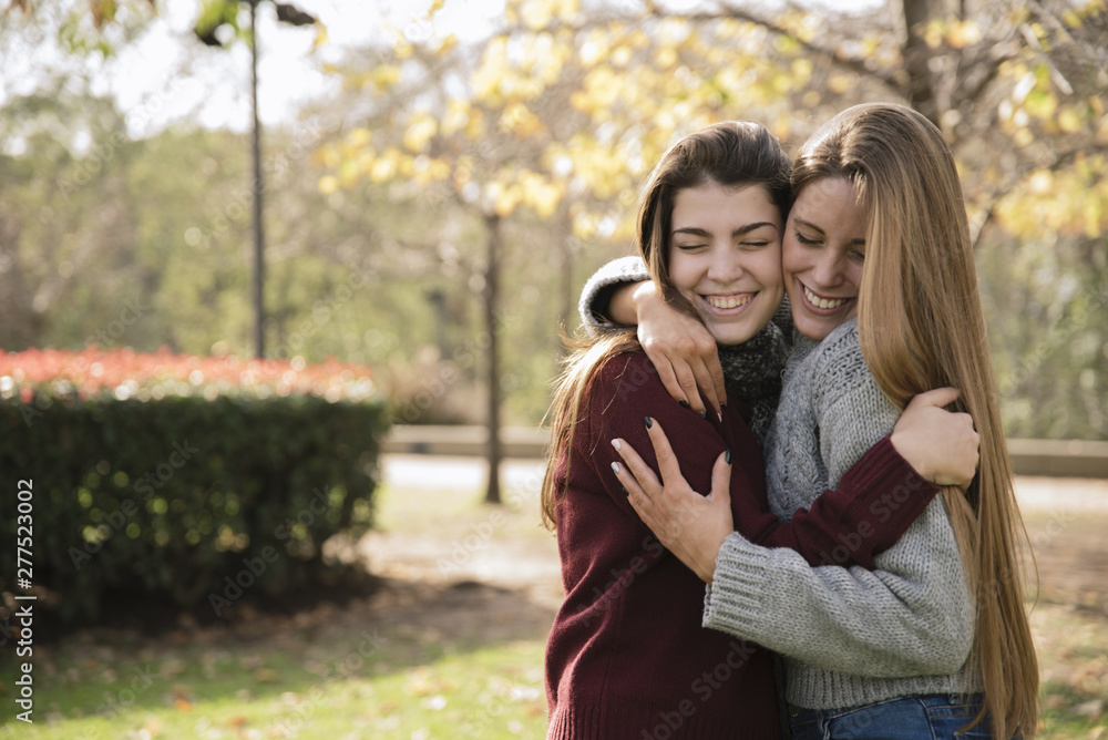 Medium shot two hugging young women in the park Medium shot two hugging young women in the park