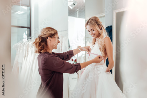 Valokuva Tailor taking measures of a young woman.