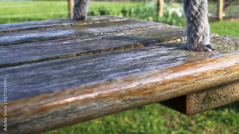 CLOSE UP view of wooden swing seat gently swaying in the wind CLOSE UP view of wooden swing seat gently swaying in the wind