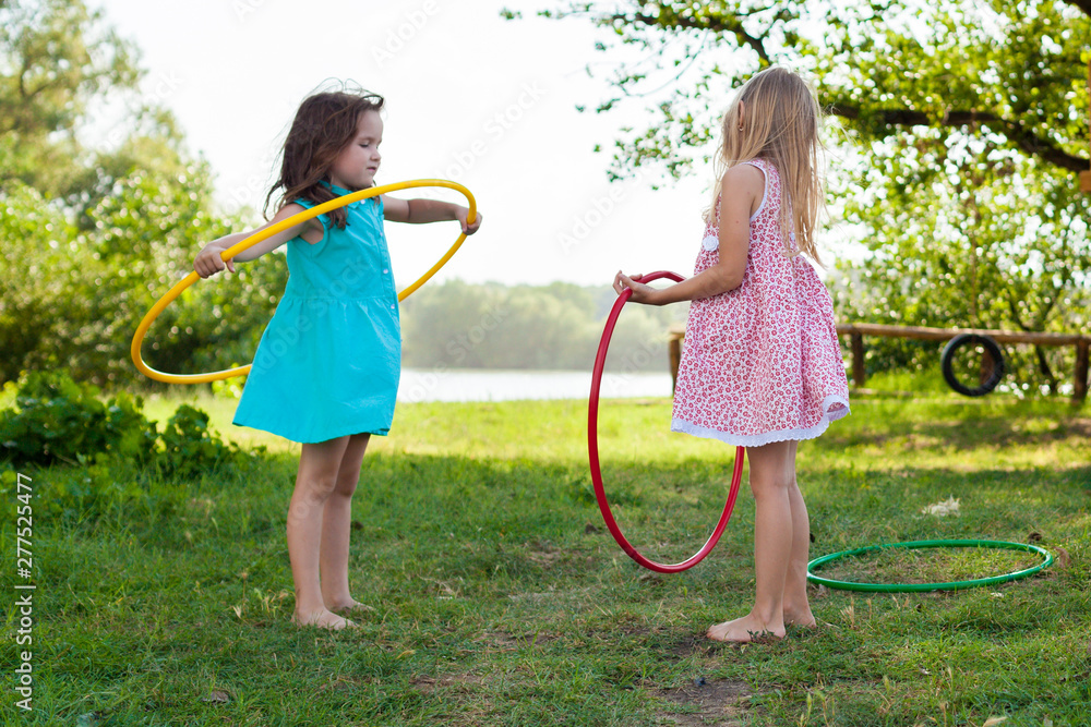 children play with hula Hoop and train their skills in summer. Cheerful  Exercise Concept . happy girls