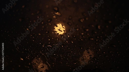 Night traffic lights. Road in the headlights of a car window, rain drops on the windshield. Bokeh and glare, reflections night lights. Car headlights photo