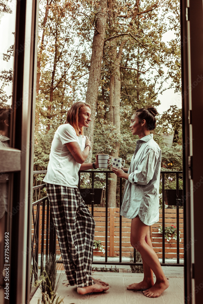 Pretty close couple staying on the balcony and talking to each other Pretty close couple staying on the balcony and talking to each other