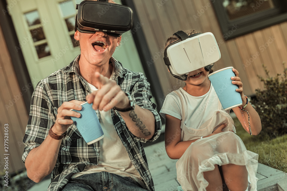 Laughing active father in black and white shirt playing in VR-helmet Laughing active father in black and white shirt playing in VR-helmet