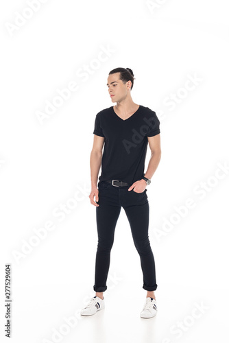 full length view of brunette young man in black clothes with hand in pocket isolated on white