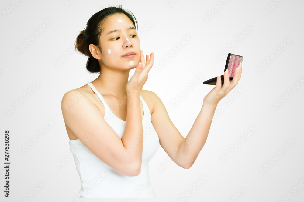 An asian woman put lotion on her face An asian woman put lotion on her face