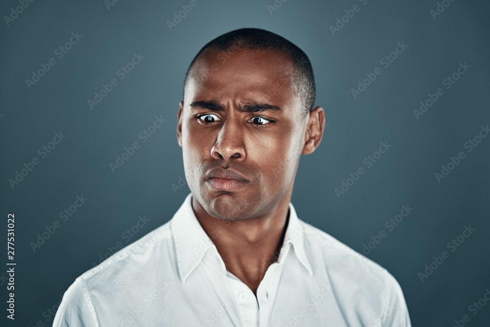 Obraz premium Cross eyed man. Handsome young African man in shirt making a face while standing against grey background