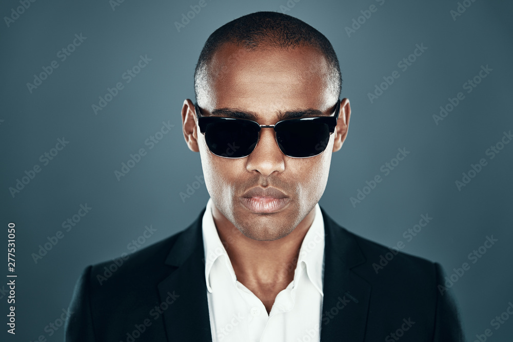 Perfect in every way. Charming young African man in full suit looking at camera while standing against grey background Perfect in every way. Charming young African man in full suit looking at camera while standing against grey background