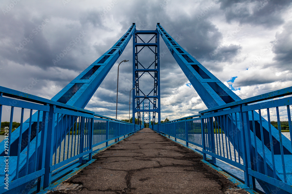 Scenic metal pedestrian bridge in blue across the river