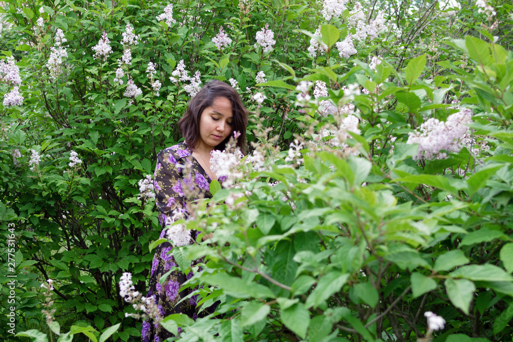 Portrait of beautiful young woman in black-purple dress in a garden with blooming lilac bushes. Portrait of beautiful young woman in black-purple dress in a garden with blooming lilac bushes.