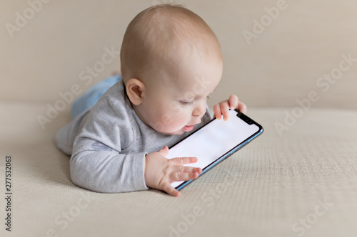 Little baby child is playing with smartphone learning how to communicate with new technologies