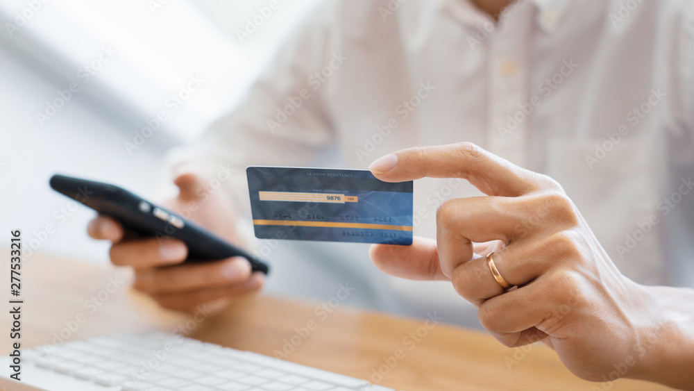 Hand of man in casual shirt paying with credit card and using smart phone for online shopping making orders via the Internet using mobile bank application, Online payment. Hand of man in casual shirt paying with credit card and using smart phone for online shopping making orders via the Internet using mobile bank application, Online payment.