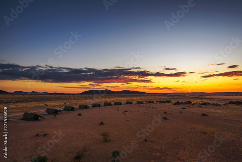 Sunset above small chalets of a desert lodge near Sossusvlei in Namibia