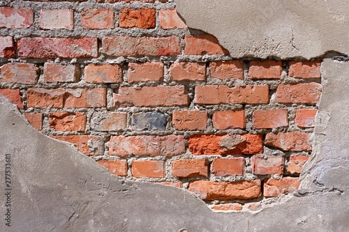 A dilapidated red brick wall on which plaster fell off (fragment)