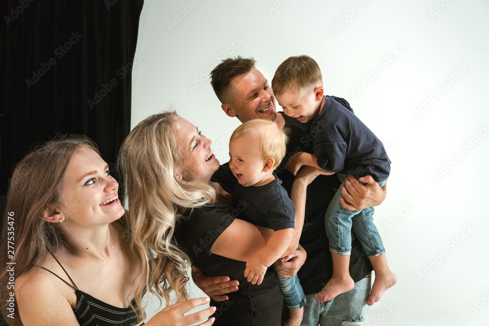 Young family spending time together and smiling. Parents with young daughter and little sons playing and laughting. Family lifestyle. Mother's, father's day, togetherness, parenthood, kid's rights