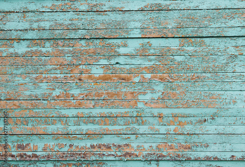 exfoliated blue paint on the wall of wooden boards