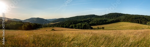 Panoramic view of the green hills flooded with warm rays of the setting sun