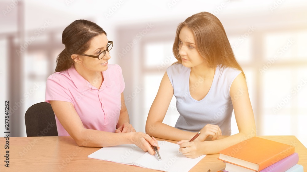Mother helping happy daughter with homework on background Mother helping happy daughter with homework on background
