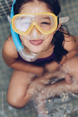 grimacing little girl with snorkel goggles at tub