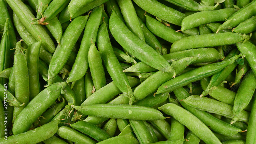 Fresh pea pods as background. Top view.