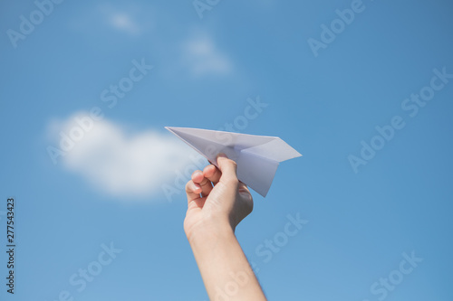 Men's hands holding a white paper rocket with a bright blue background.