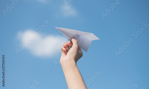 Men's hands holding a white paper rocket with a bright blue background.