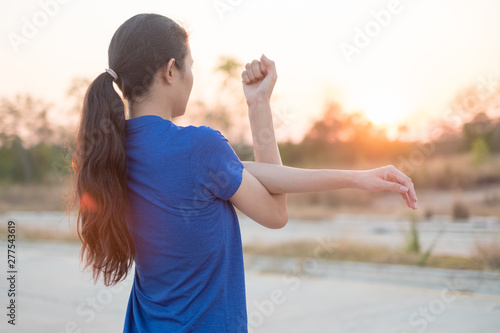 Young women exercise before exercising at the park. She stretched her arms for physical examination with the background of the sun falling.