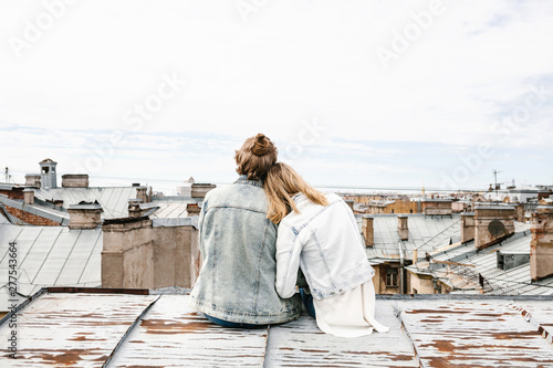 A young couple sits on the roof and admires a beautiful view of the city. Romance, love and trusting relationships. Or he dream or digital detox together.