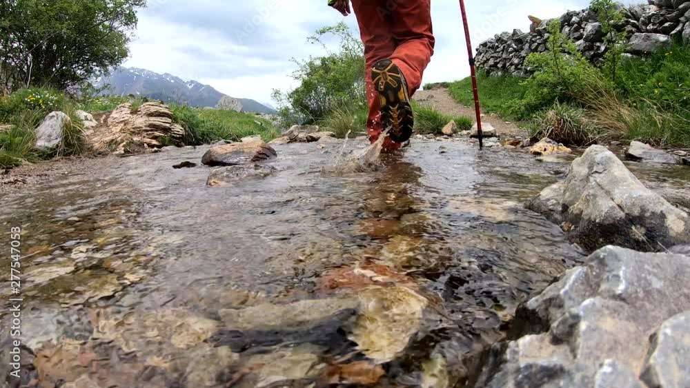 hiker woman crossing a small stream in the mountain hiker woman crossing a small stream in the mountain