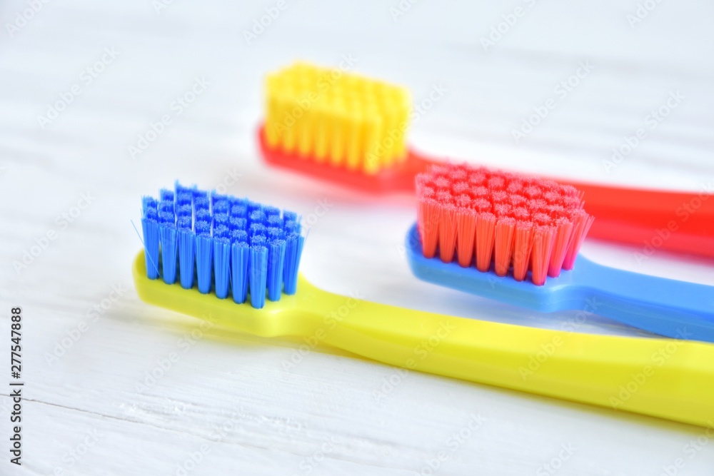 Colorful toothbrushes with selective focus on blurred neutral background. Dental tools for daily teeth protection. Multicolored plastic toothbrush with bright bristles with soft focus. Oral hygiene Colorful toothbrushes with selective focus on blurred neutral background. Dental tools for daily teeth protection. Multicolored plastic toothbrush with bright bristles with soft focus. Oral hygiene